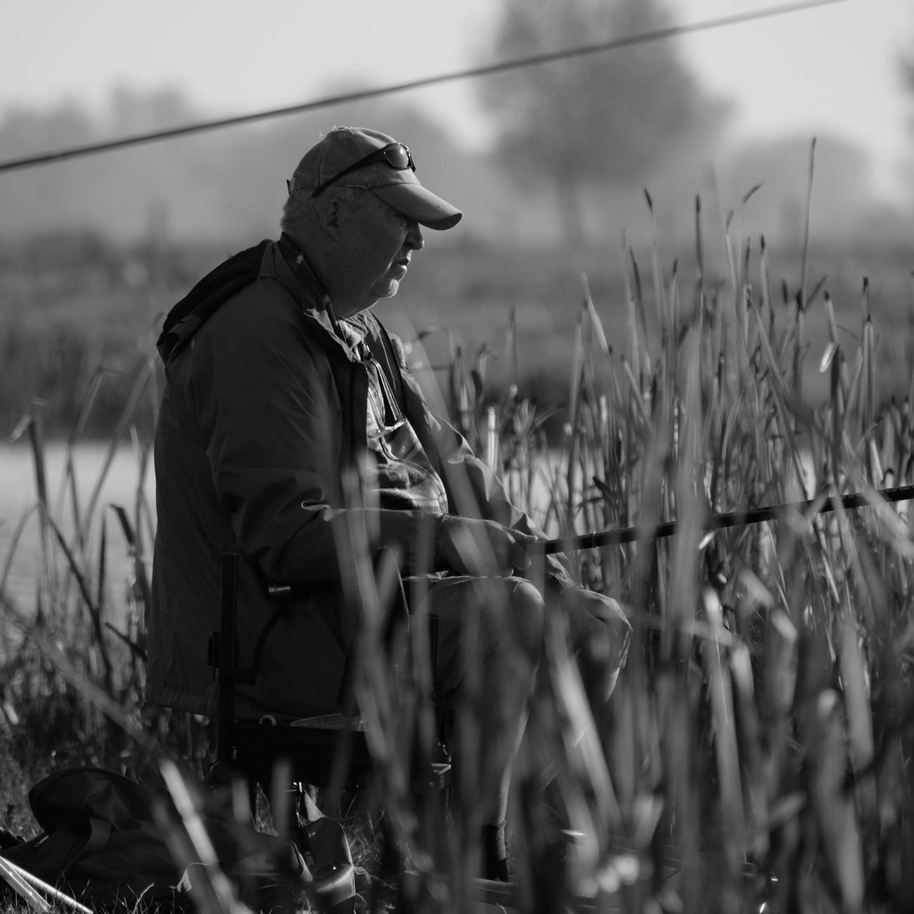 Angler holding spinning rod with predator lure by shoreline